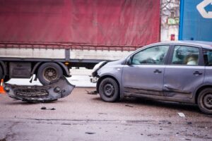 A damaged car on the road after collision with semi truck