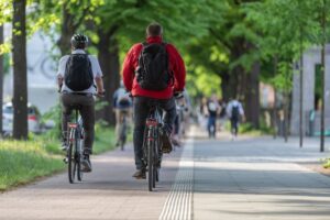 Male cyclists with backpacks on bike path in avenue