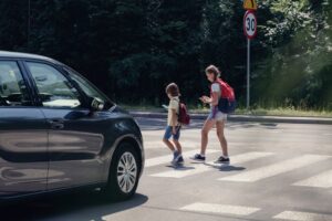 Kids are crossing road while a car coming towards them