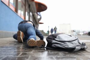 Man with backpack lying on slippery sidewalk after fall closeup