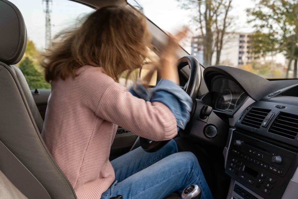 Frustrated female driver hitting the steering wheel in anger while sitting in her car. Frustrated female driver hitting the steering wheel in anger while sitting in her car.