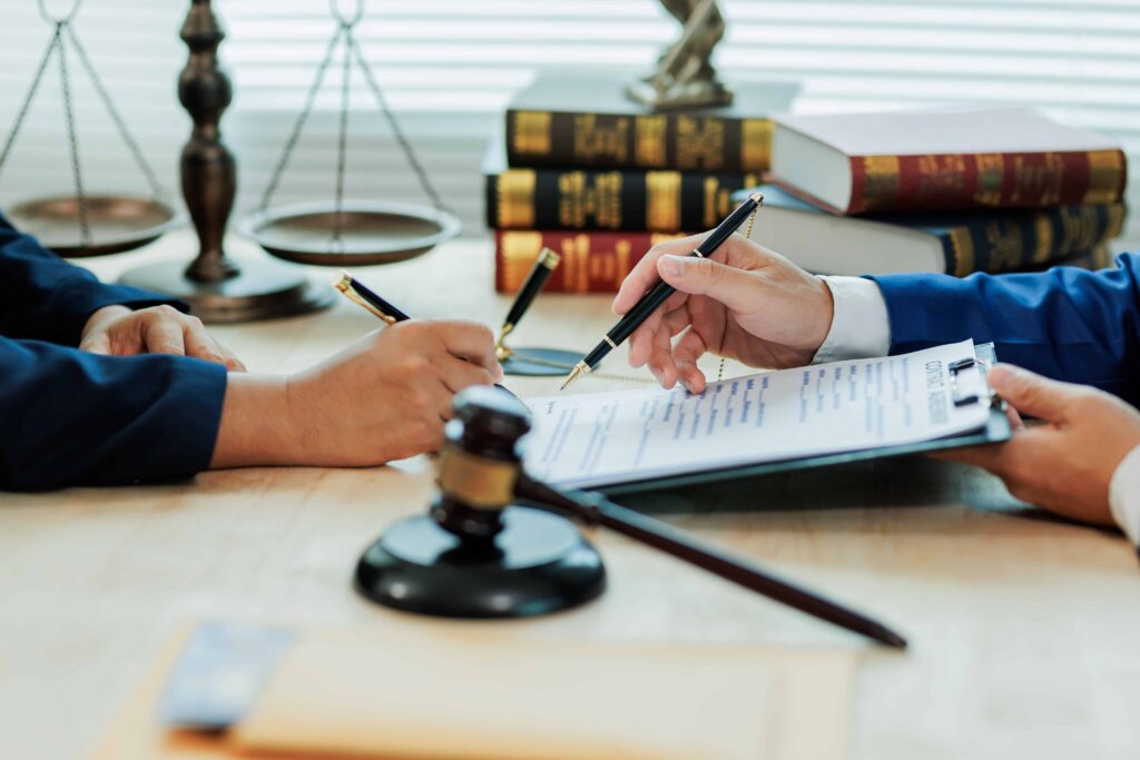 Lawyer consulting a client and reviewing legal documents at a law office desk.