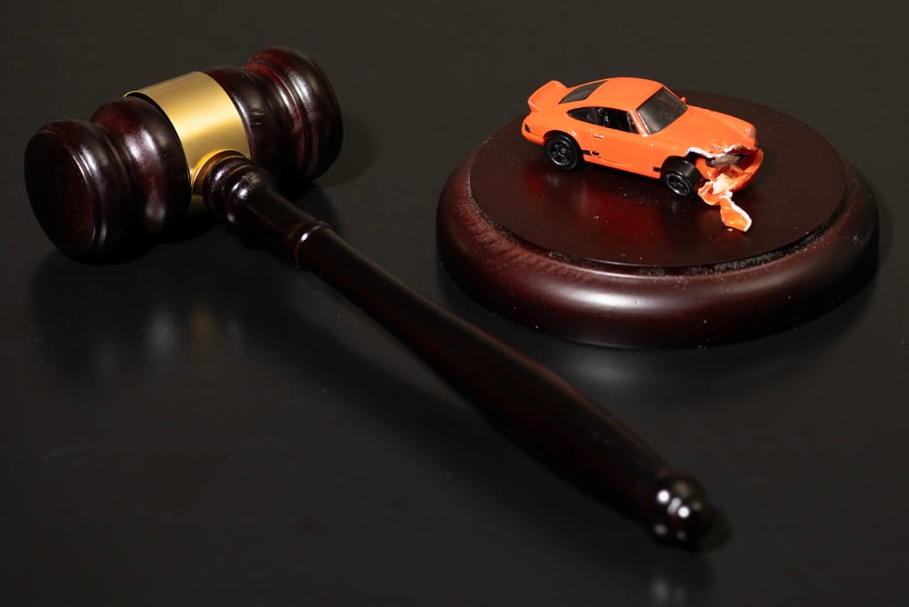Damaged toy car next to gavel representing car accident court case