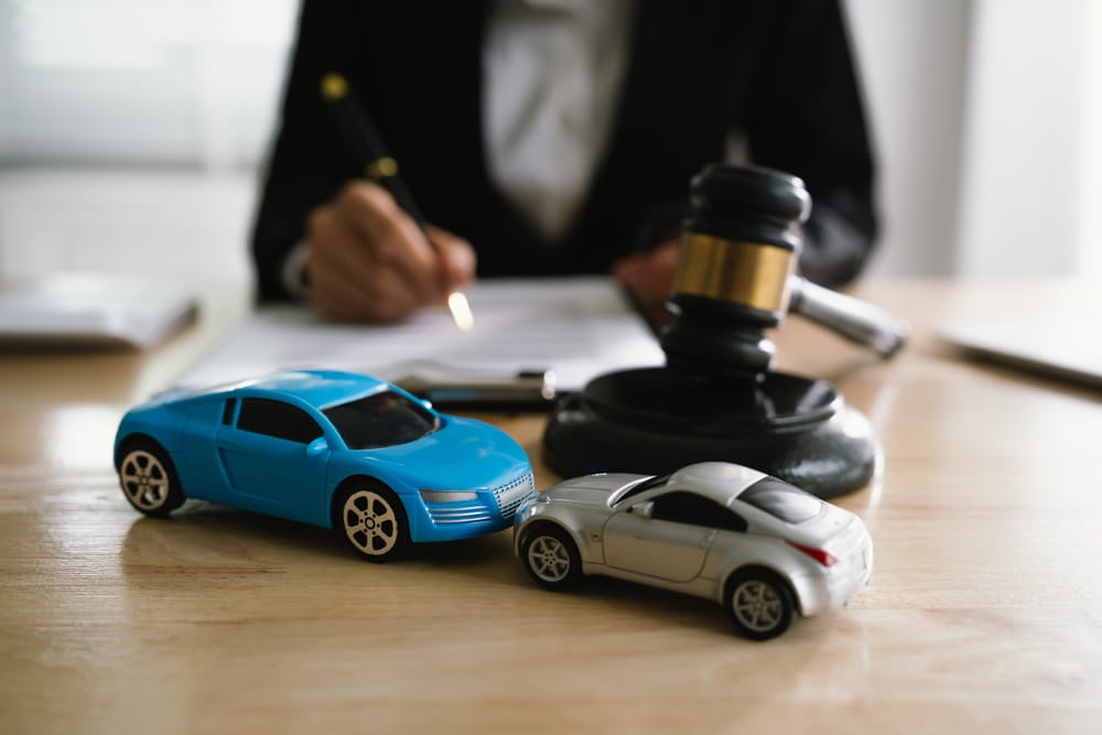 Car accident lawsuit concept with toy cars and gavel on desk