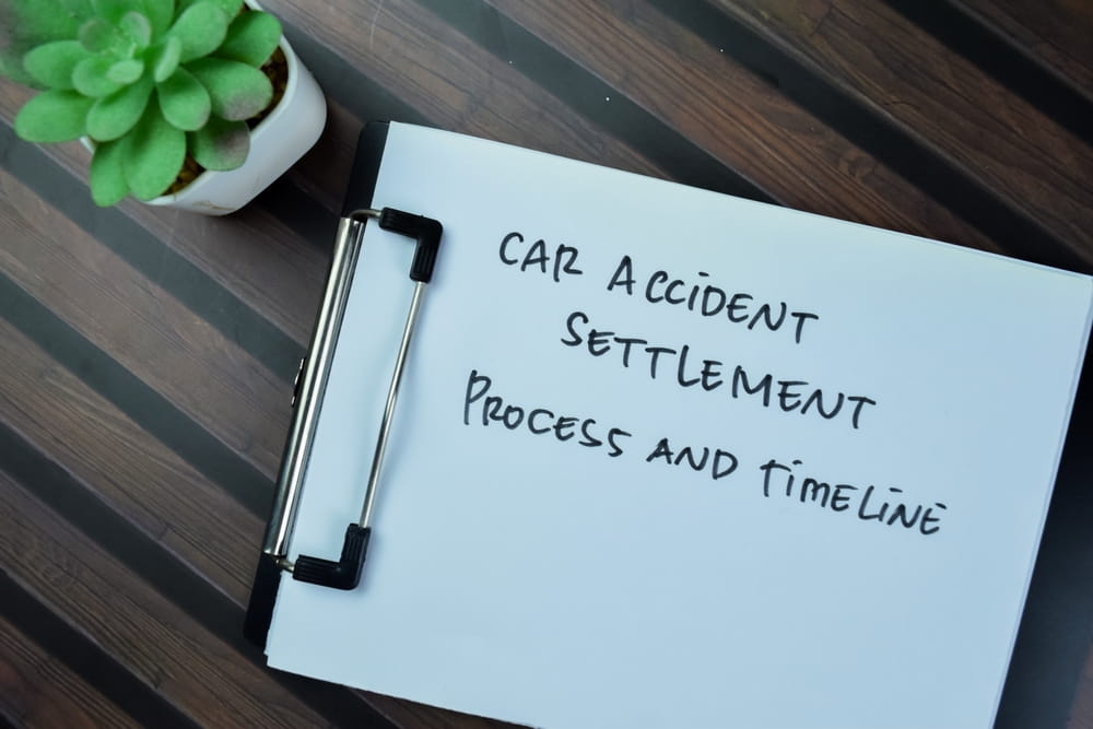 Car accident settlement process and timeline written on clipboard