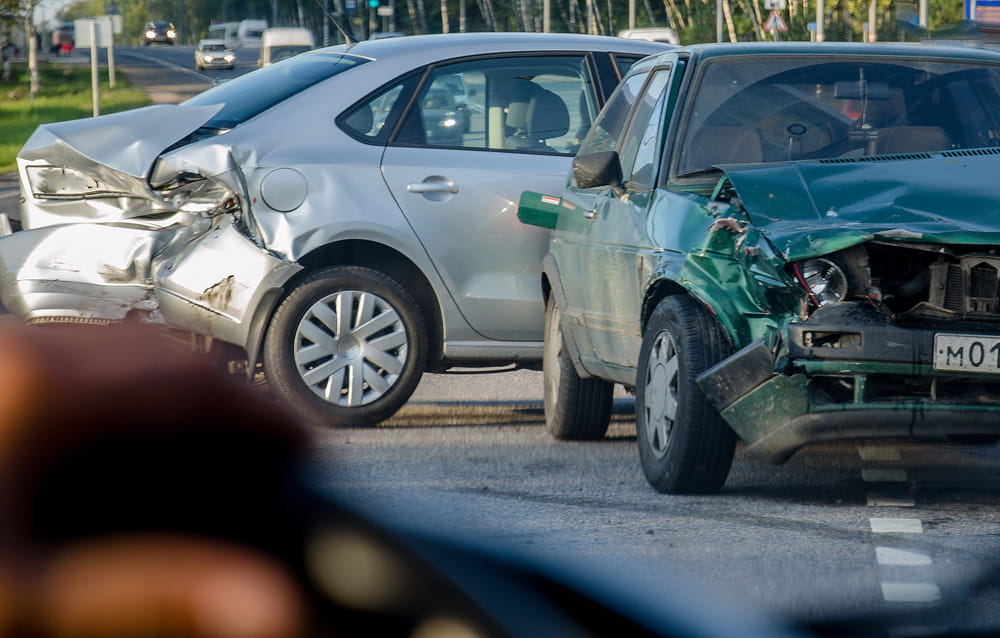 Multi-vehicle accident scene with damaged cars on roadway