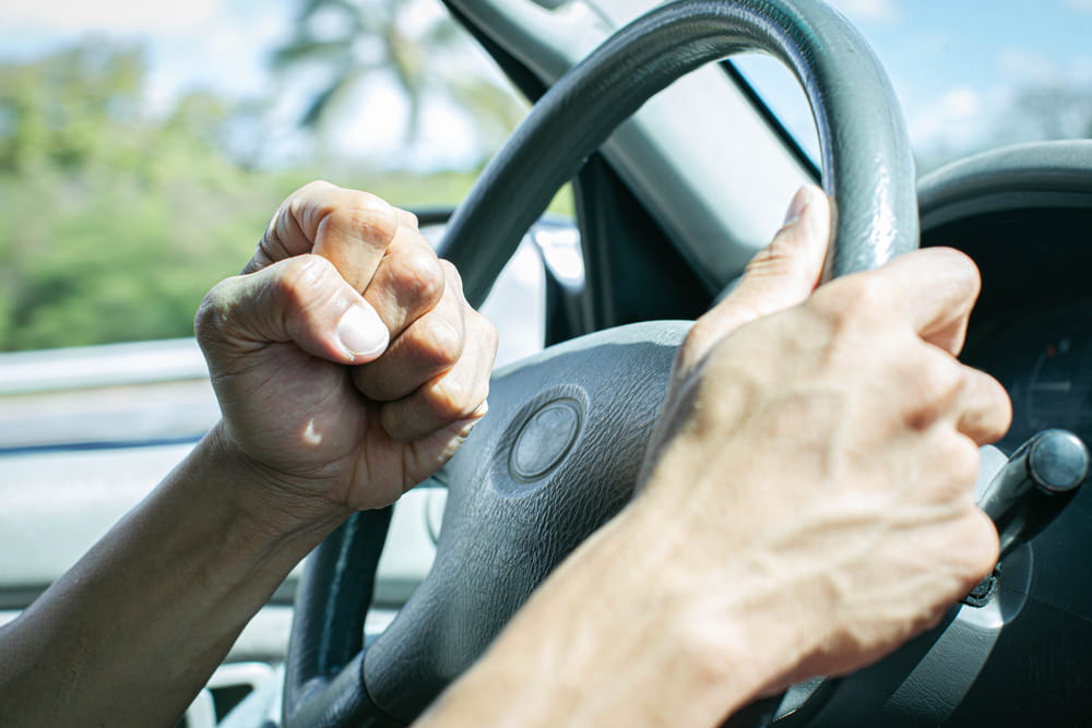 driver showing aggressive behavior gripping steering wheel tightly