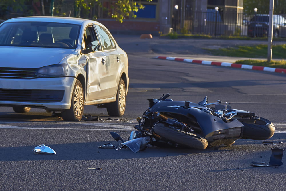motorcycle crash at intersection with damaged car and debris