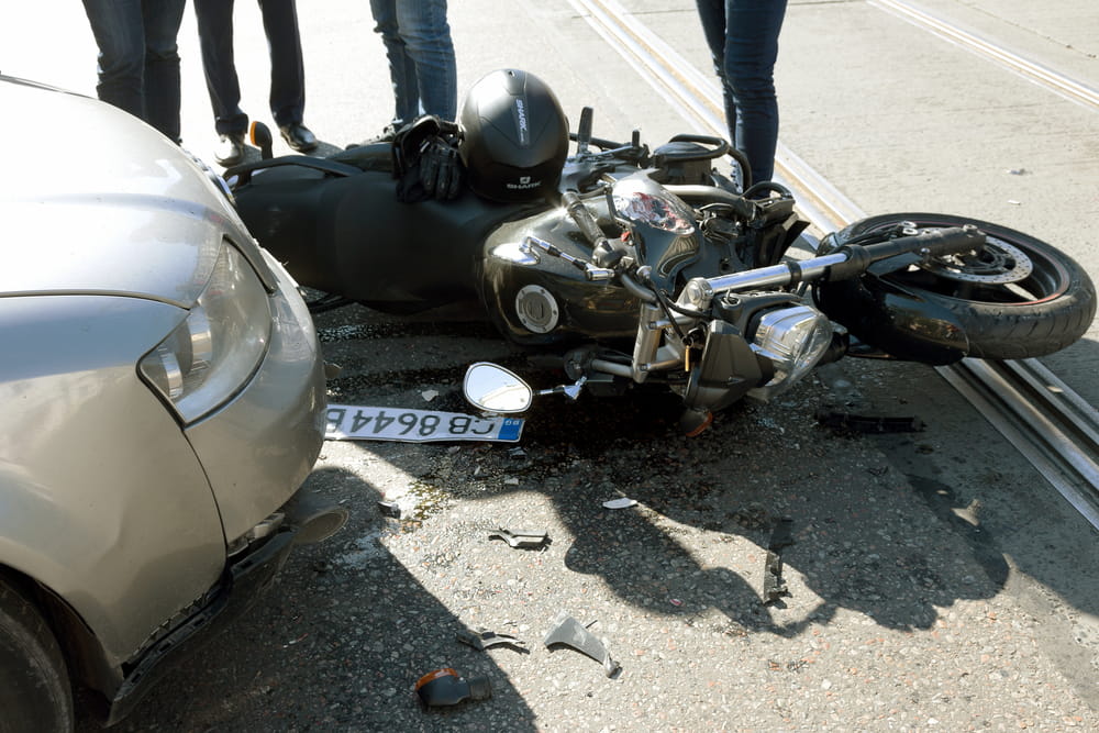 motorcycle accident scene involving car and fallen bike after collision