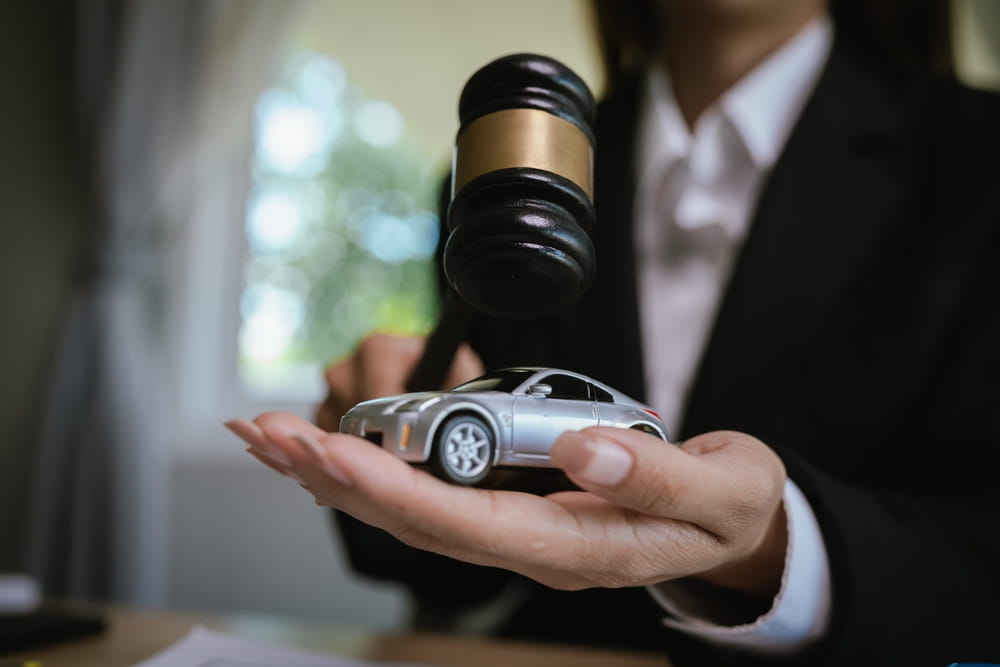 Judge’s gavel above a model car, symbolizing legal disputes involving car accident damage and insurance liability claims.