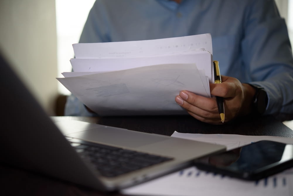 Individual reviewing paperwork and legal documents related to an insurance claim and settlement negotiation.