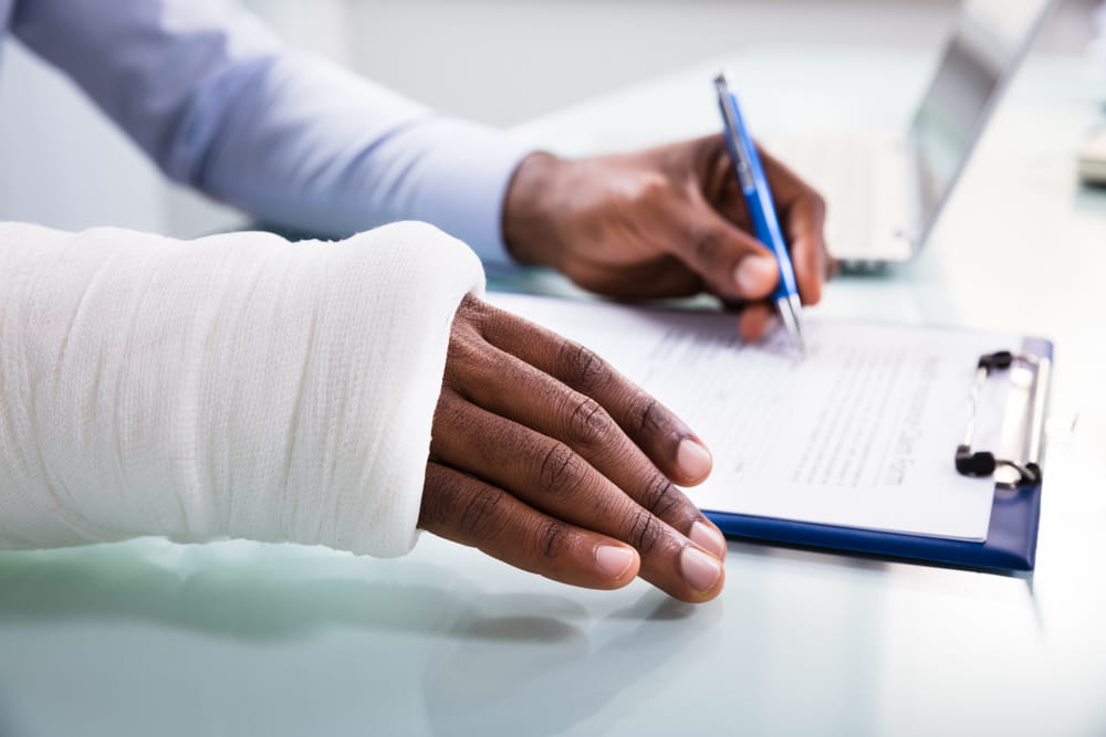 Injured person with an arm cast reviewing paperwork during a legal or medical consultation after an accident injury.