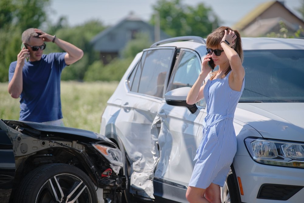 Two drivers standing beside damaged cars calling for help after a car accident